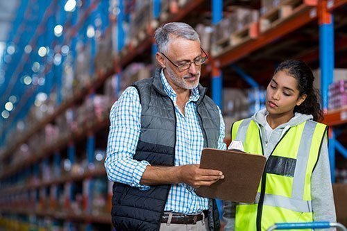 older man showing clipboard to young female worker