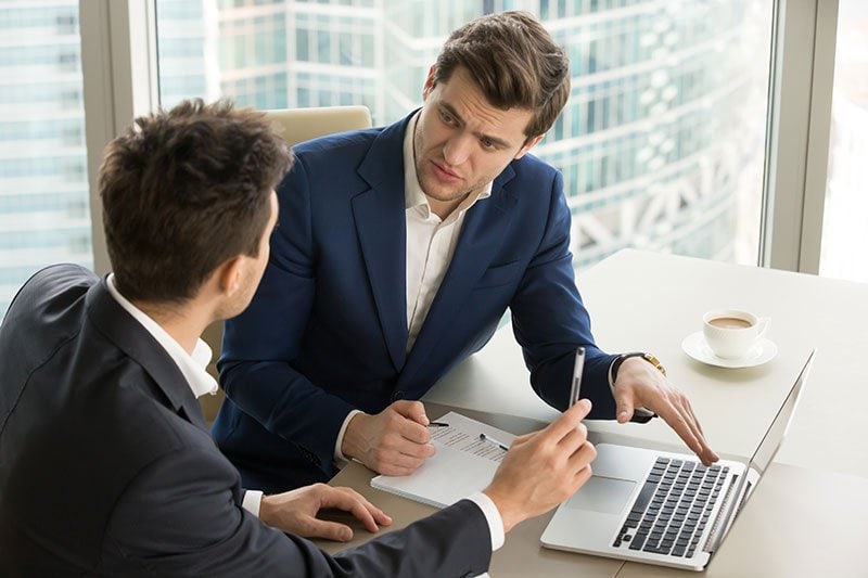 two men sitting at a desk talking